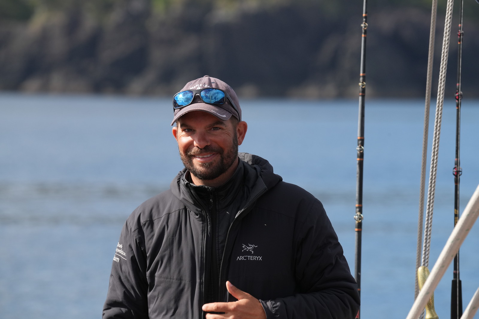 A portrait of Tristan Ray-Wilks, smiling outdoors with scenic surroundings in the background.